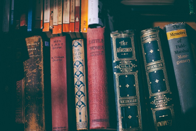 Several books on a shelf with titles and authors on the spines